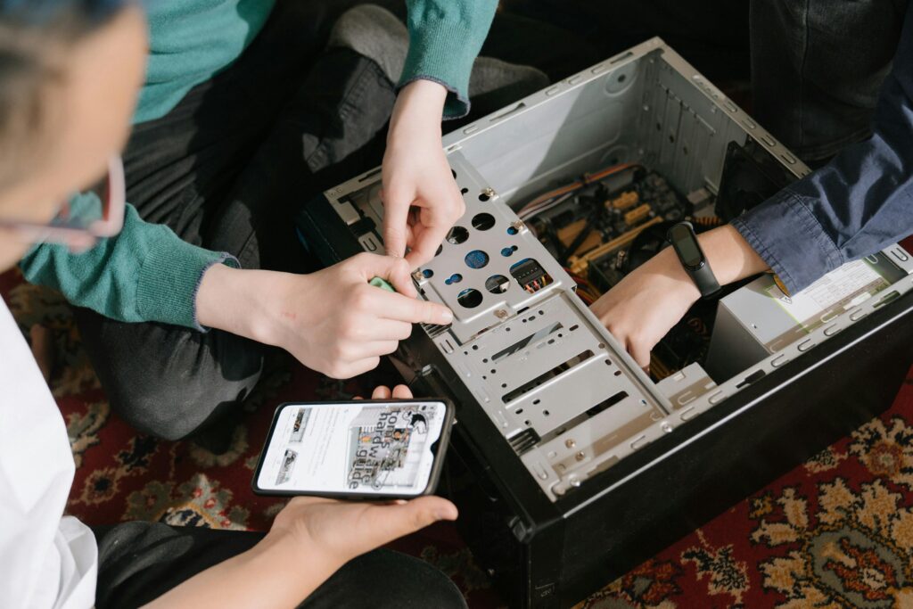 A close-up of hands fixing a computer with guidance from a mobile device.